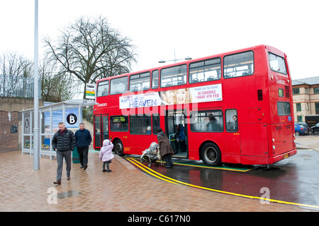 Les passagers d'un bus à impériale rouge dans Transdev livery attendant à un arrêt de bus. Banque D'Images