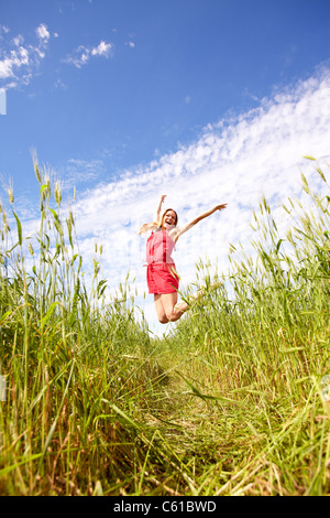 Photo de happy girl sautant par-dessus l'herbe verte sur journée d'été Banque D'Images