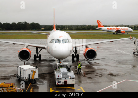 L'appui au sol service à l'aide d'un tracteur pushback pour déplacer un Airbus d'Easyjet sur la voie de circulation à l'aéroport d'Édimbourg en Écosse Banque D'Images