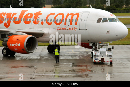 L'appui au sol service à l'aide d'un tracteur pushback pour déplacer un Airbus d'Easyjet sur la voie de circulation à l'aéroport d'Edinburgh Scotland UK Banque D'Images