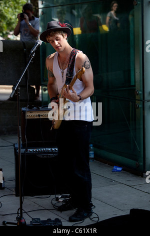 Portrait en longueur d'un busseur de sexe masculin jouant une guitare, Southbank, Londres, Angleterre, Royaume-Uni. Banque D'Images