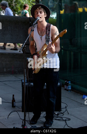 Portrait en longueur d'un busseur de sexe masculin jouant une guitare, Southbank, Londres, Angleterre, Royaume-Uni. Banque D'Images