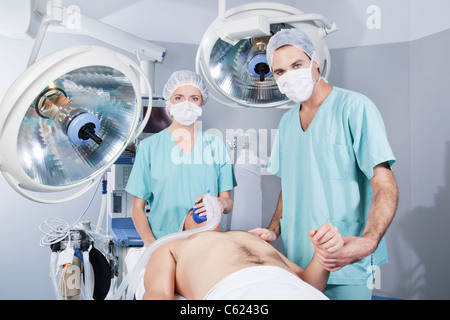 Femme médecin l'application du gaz et de l'homme médecin contrôle de taux d'impulsions du patient Banque D'Images