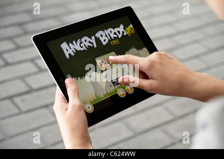 Une femme à l'extérieur jouer au jeu Angry Birds sur Apple ipad2 Banque D'Images