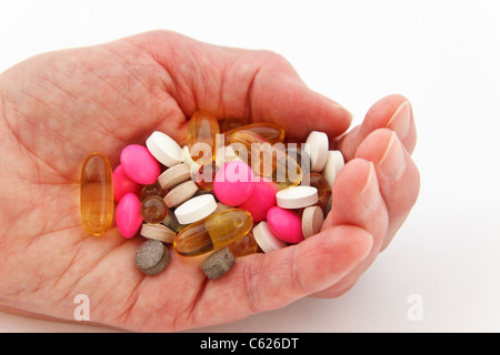 Femme âgée tenant une sélection de médicaments d'ordonnance et de suppléments différents dans la paume d'une main. Angleterre Royaume-Uni Grande-Bretagne Banque D'Images
