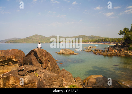 Un homme pratique le yoga méditation sur les rochers à la station touristique populaire de plage de Palolem, Goa, Inde Banque D'Images