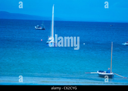 Bateau à rames et bateau à voile sur la mer bleu calme à Cornwall, en prise avec l'établissement d'un éclairage Banque D'Images