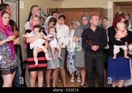 Le baptême d'un petit enfant dans une église russe orthodoxe chrétienne. Les gens qui ont des enfants dans la salle avant qu'un baptême. Banque D'Images