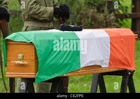 Gants paramilitaires de l'IRA et béret sur un cercueil avec un drapeau tricolore irlandais. De l'IRA, il en arrière-plan. Banque D'Images