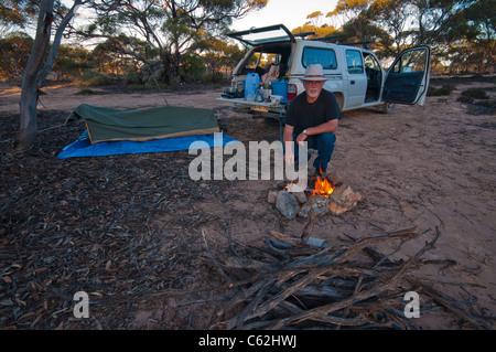 Homme avec feu de camp et dressa le swag dans l'outback australien Banque D'Images