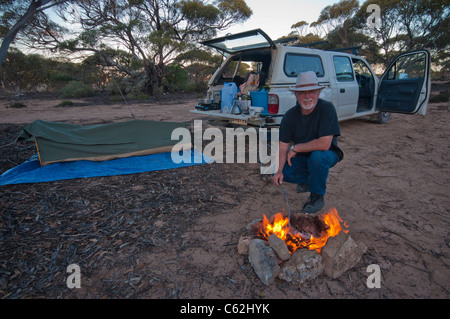 Homme avec feu de camp et dressa le swag dans l'outback australien Banque D'Images