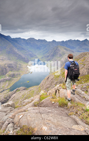 Walker à admirer la vue vers la Black Cuillin ridge au Loch Coruisk de sommet de Sgurr na ires, Isle of Skye Banque D'Images