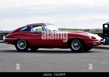 Profil de côté rouge E-type Jaguar en 50e année anniversaire sur parking Banque D'Images