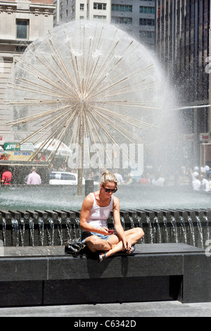 Jeune femme en vêtements d'été bien juste à côté de cigarette détend jolie fontaine pissenlit Sixième Avenue Manhattan NY Banque D'Images