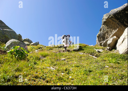 Male hiker walking up sentier raide contre le ciel bleu, dans les Alpes françaises. Banque D'Images