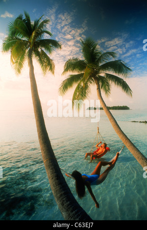 Couple hanging sous des palmiers au coucher du soleil sur Meeru Island aux Maldives Banque D'Images
