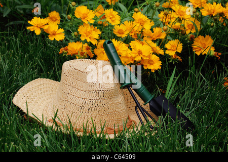 Chapeau de paille, pot d'arrosage et de jardinage dans le jardin Banque D'Images