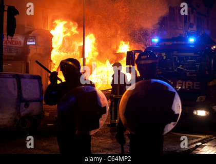 Les agents de police et les pompiers se tenir en face d'un effondrement des capacités de gravure à Croydon, au cours de l'Aug 11 émeutes. Banque D'Images