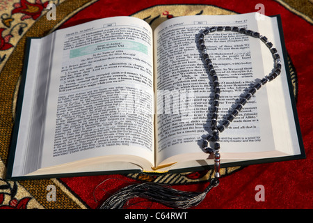 Noble Coran traduit version anglaise et chapelet sur un tapis de prière musulmane Banque D'Images