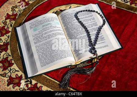 Noble Coran traduit version anglaise et chapelet sur un tapis de prière musulmane Banque D'Images