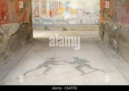 Entrée d'une maison qui a été converti en un gymnase, Pompéi. Une mosaïque représente deux athlètes et les murs présentent des fresques. Banque D'Images