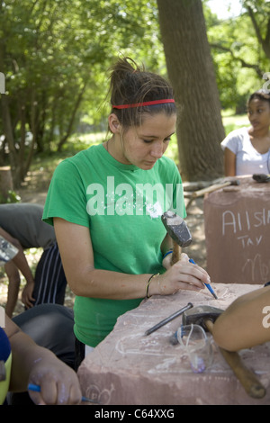 College student fonctionne sur la sculpture sur pierre pour un parc en cours de construction par les jeunes du quartier et les bénévoles en centre-ville de Detroit Banque D'Images