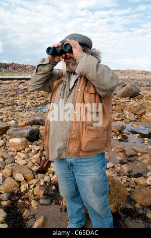 Un guide de nature et de nature sauvage qui regarde à travers des jumelles sur les appartements de marée de la baie d'Hudson près de Churchill, Manitoba, Canada. Banque D'Images