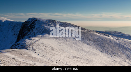 Les randonneurs d'hiver neige descendre une couverts Nethermost Pike avant dernière lumière. Lake District, Cumbria, Royaume-Uni Banque D'Images