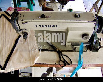 Machine à coudre et ciseaux de tailleurs bien utilisés dans le magasin de tailleurs de bord de route, Bali. Banque D'Images