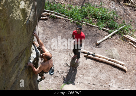 Un adulte male rock climber étant belayed à partir de ci-dessous qu'il perfectionne sa technique sur un affleurement de grès dans le Kent, au sud de Londres. Banque D'Images