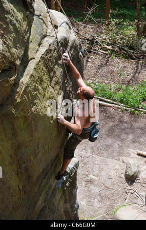 Male rock climber adultes exerçant ses compétences et la technique sur un affleurement de grès dans le Kent, au sud de Londres, au Royaume-Uni. Banque D'Images