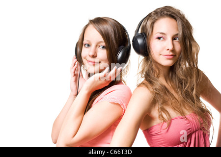 Partagez votre musique, deux gorgeosu brunette adolescents s'amusant avec headphnes, isolé sur blanc. Banque D'Images