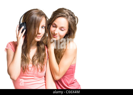 Deux magnifiques jeunes filles brune partageant une tune dans leurs écouteurs, isolé sur fond blanc. Banque D'Images