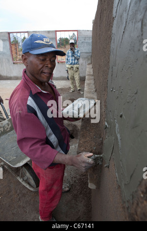 Un travailleur de la construction aide à construire une école au Malawi, Afrique du Sud Banque D'Images