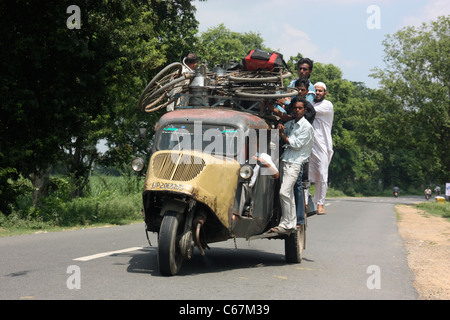 Les passagers s'accrochent au toit d'un monde vintage trois roues Bajaj Tempo bus taxi sur la campagne du Pendjab au nord de l'Inde Banque D'Images