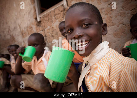 Un garçon de l'école de boissons une tasse de Amuria, Ouganda, Afrique de l'Est. Banque D'Images