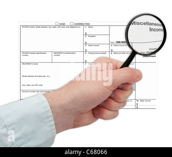 Main tenant Loupe sur Formulaire d'impôt Banque D'Images