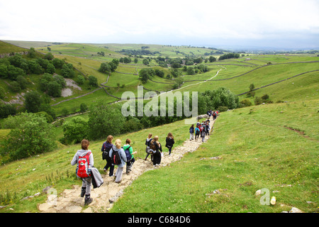 Un groupe d'enfants de l'école de descendre les marches de pierre du haut de Malham Cove, dans le Yorkshire Dales National Park, England, UK Banque D'Images