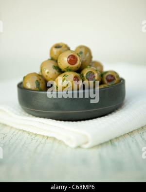 Olives vertes farcies aux poivrons rouges à l'huile d'olive et les herbes dans un pot Banque D'Images