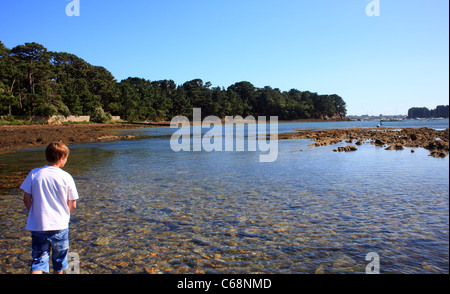 Boy paddling sur causeway à Ile de Berder, Larmor-Baden, Morbihan, Bretagne, France Banque D'Images