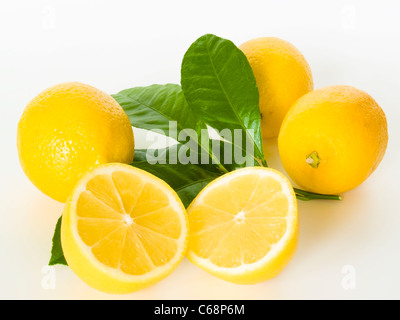 Blättern mit drei Zitronen, davor liegt eine Zitrone aufgeschnittene | trois citrons avec feuilles, à l'avant est un citron coupé Banque D'Images