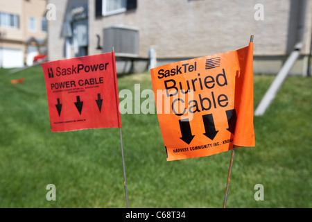 Drapeaux d'avertissement pour l'alimentation et les câbles téléphoniques enterrés sur une propriété gérée Saskatoon Saskatchewan Canada Banque D'Images