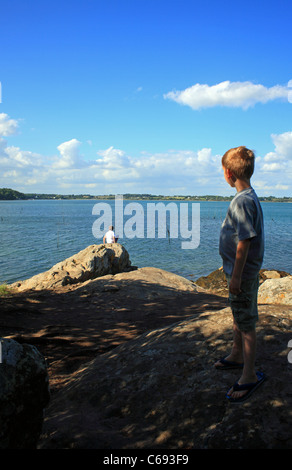 Les garçons debout sur les rochers à la recherche à vue sur Golfe du Morbihan, sur l'Ile de Berder, Larmor-Baden, Morbihan, Bretagne, France Banque D'Images