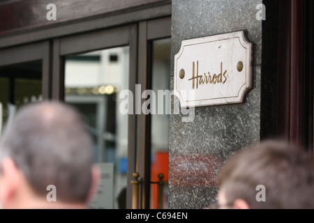 Un Harrods situées sur l'avant de son magasin de Knightsbridge du flou têtes des personnes au premier plan Banque D'Images