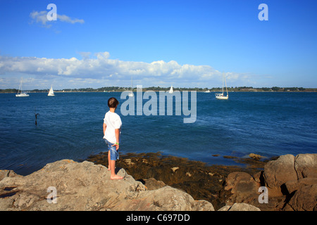 Boy looking at view sur le golfe du Morbihan à partir de l'Ile de Berder, Larmor-Baden, Morbihan, Bretagne, France Banque D'Images