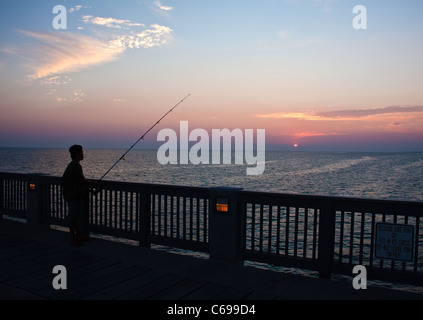 Pêcheur solitaire au coucher du soleil sur la jetée à Panama City Beach, Floride, USA Banque D'Images