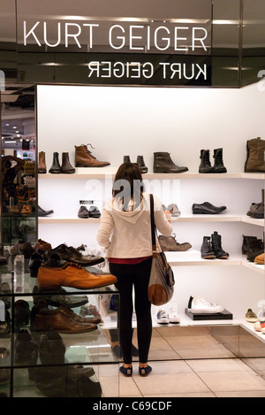 Un adolescent faisant des emplettes pour des chaussures dans la boutique de Kurt Geiger, terminal 3 de l'aéroport Heathrow de Londres, UK Banque D'Images