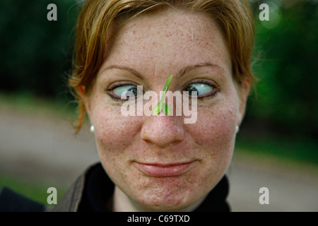 Femme avec une feuille en tirant sur son nez drôle de visage avec les yeux croisés Banque D'Images