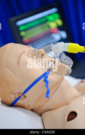 Mannequin de simulation de patient mannequin wearing oxygen mask in hospital bed vitals status monitor en arrière-plan Banque D'Images