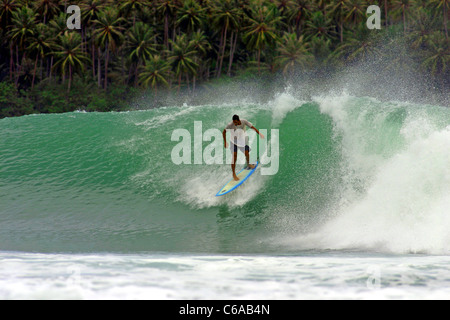 Surfant sur le point à Lagundri Bay sur l'île de Nias, Sumatra, Indonésie. Banque D'Images